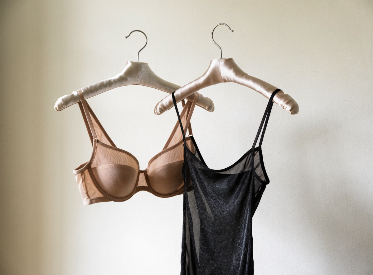 Soutien-gorge nude et nuisette noire sur cintres capitonnés contre un mur clair Image